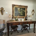 Statement furniture ensemble featuring an ornate carved console table, large framed mirror, and coordinated seating.