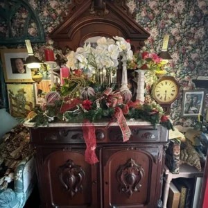 Tall antique-style dark-wood display cabinet with an elaborately carved crest, paneled doors, and decorative hardware.