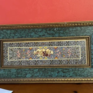 Large decorative textile or tapestry-style panel with intricate floral and geometric borders, mounted in an ornate frame.