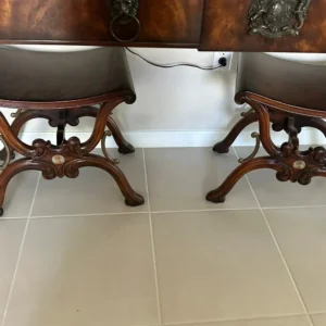 Matching pair of upholstered stools with sculptural carved-wood frames and curved legs.