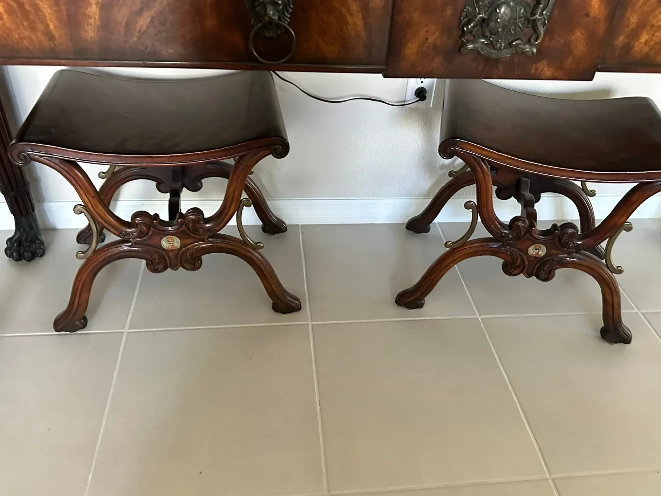 Matching pair of upholstered stools with sculptural carved-wood frames and curved legs.