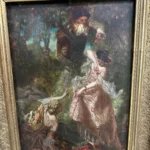 Framed romantic scene of an elegantly dressed couple in a wooded garden, presented in an ornate light-toned frame.
