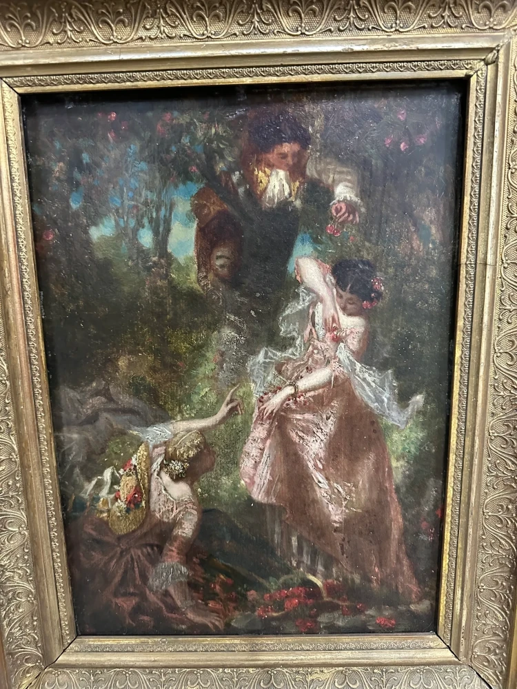 Framed romantic scene of an elegantly dressed couple in a wooded garden, presented in an ornate light-toned frame.