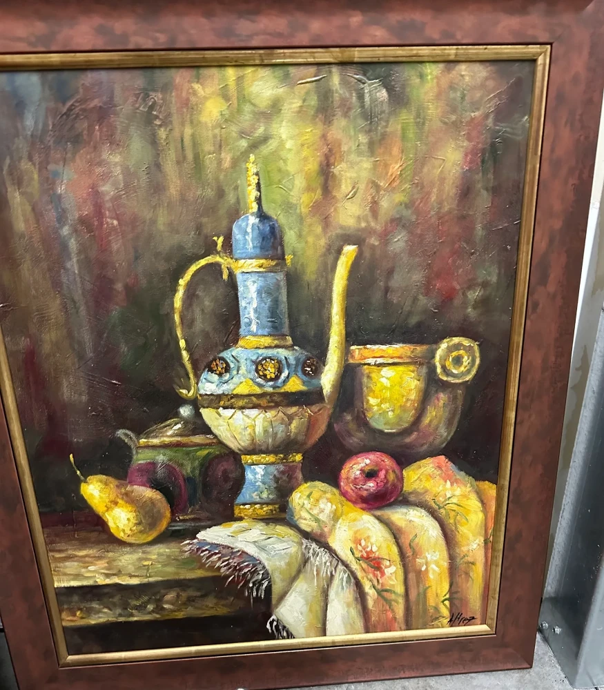 Framed still life featuring a decorative wine vessel, goblets, fruit, and bread against a dark background.